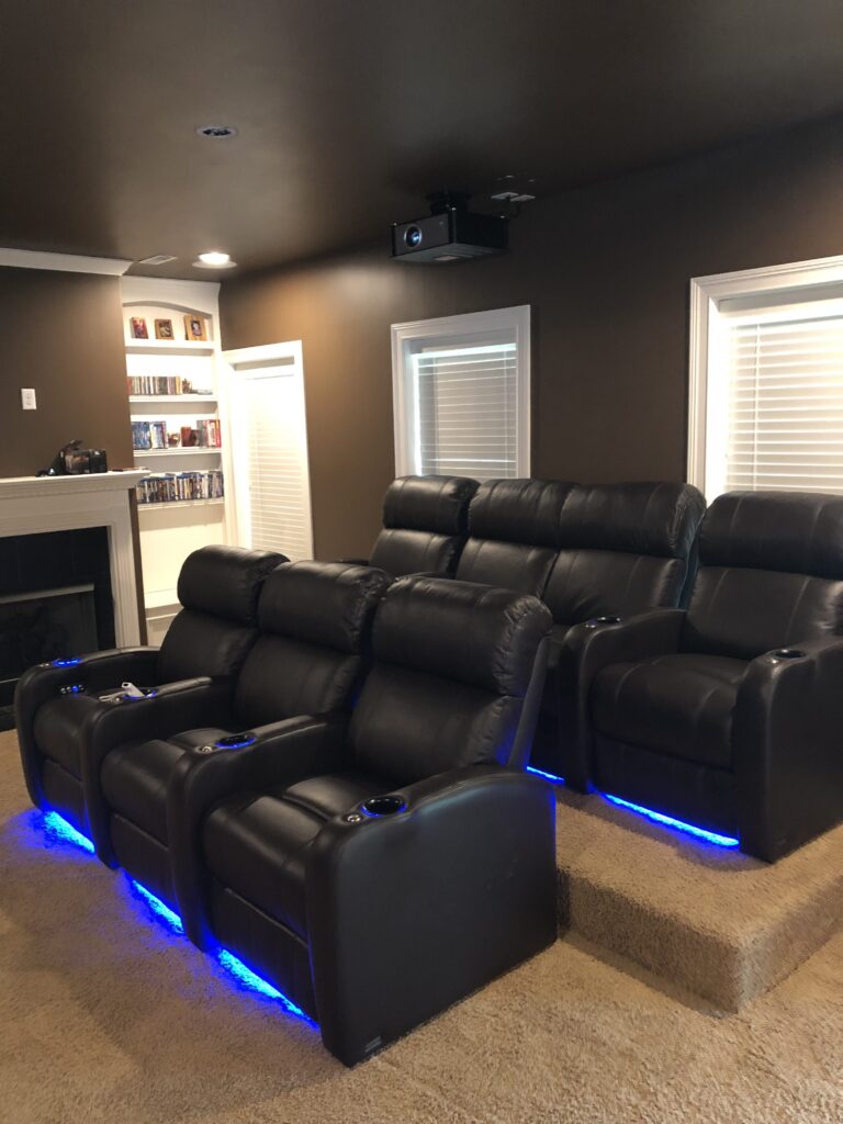 Black leather home theater seating with blue floor lighting