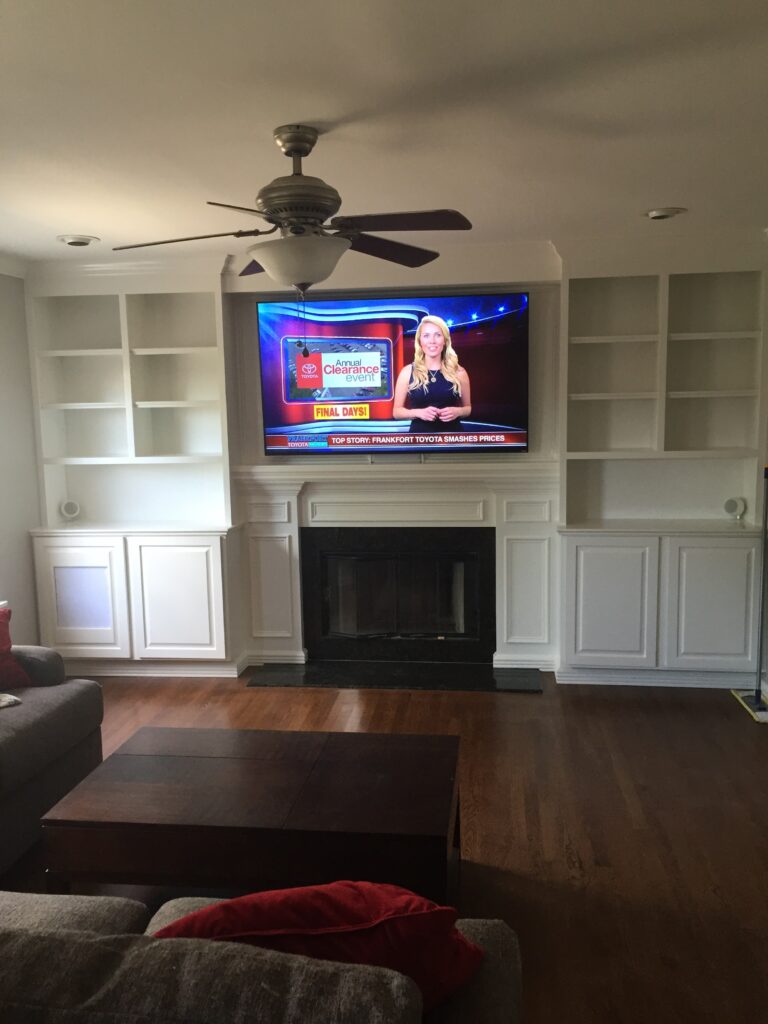 White built in home theatre system with TV and fireplace