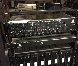 Rack-mounted wireless microphone receivers and power supply units, with labeled equipment arranged on shelves.